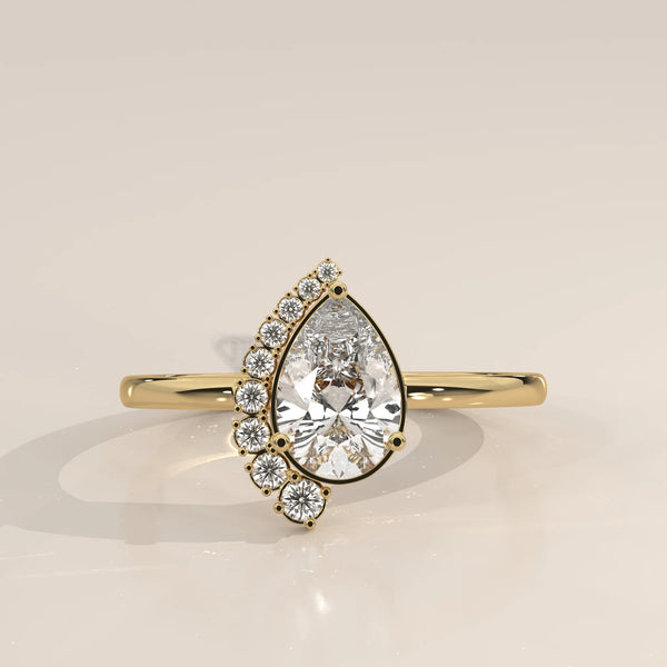 Yellow gold ring with a pear-shaped diamond and a cluster of small diamonds.