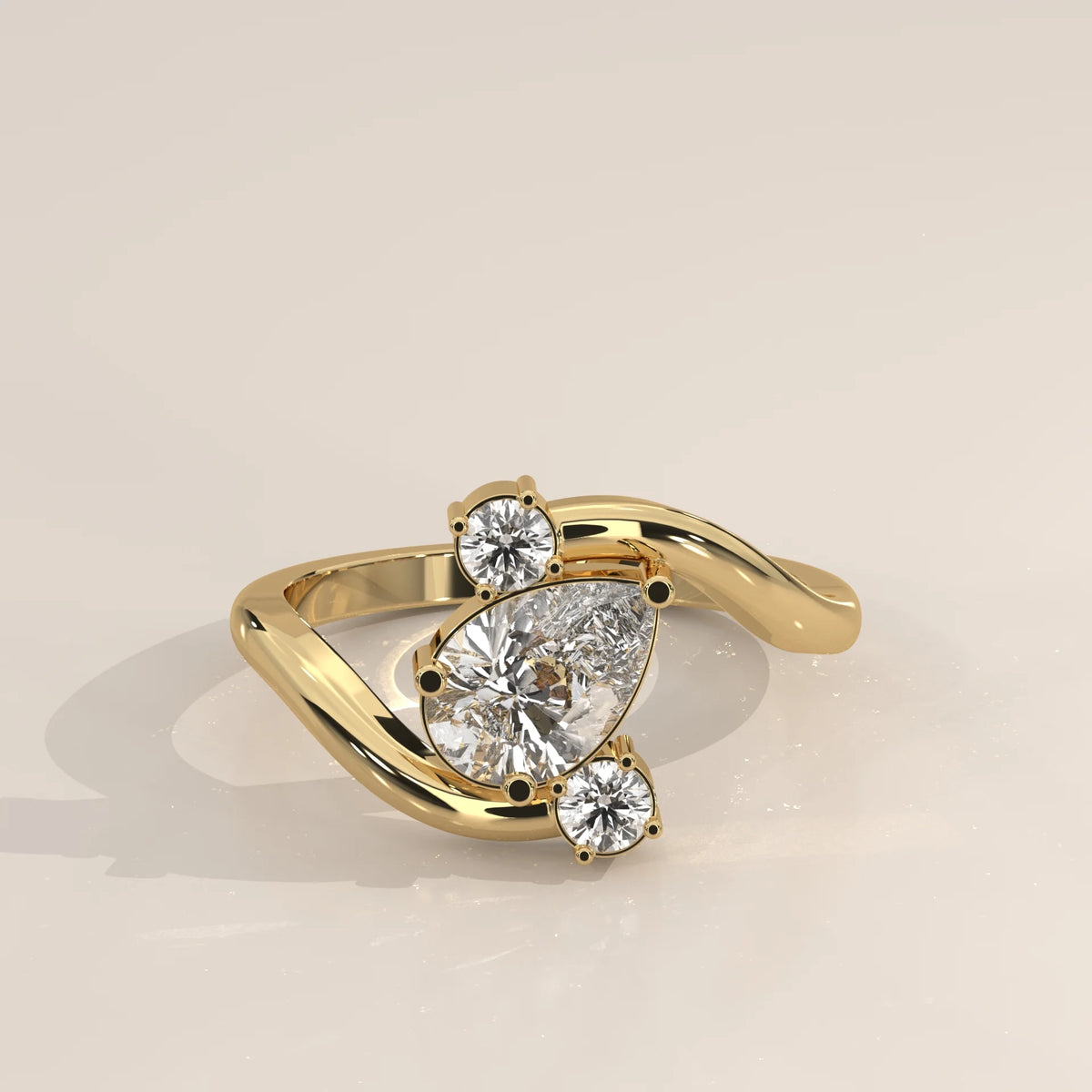 A bypass ring with a pear-cut diamond and two round diamonds in gold.