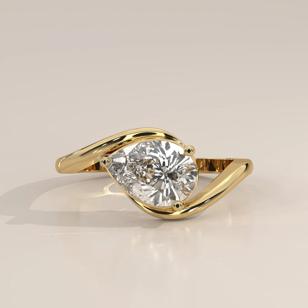 A 14k gold bypass ring with a pear-cut diamond.