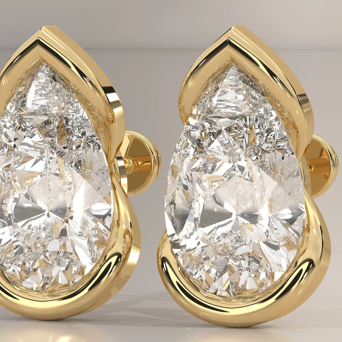 Pear Lab Grown Diamond Studs in a Curving Open Bezel in yellow gold, shown on a plain background.