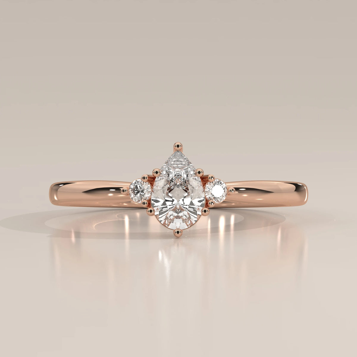 Pear lab grown diamond three stone ring in 14k rose gold, front view with round side stones