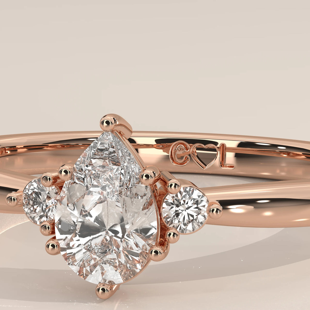 Close-up of 6x4mm pear lab grown diamond with two round side diamonds in rose gold prongs