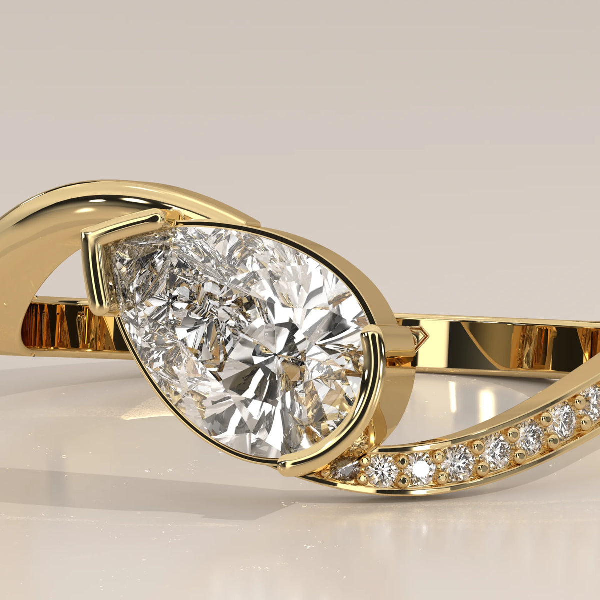 Pear Lab Grown Diamond Bypass Ring with Half Bezel and Pave Shoulder in yellow gold, shown in close-up.