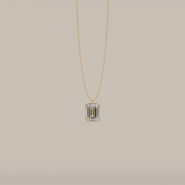 A gold pendant featuring an emerald-cut diamond.