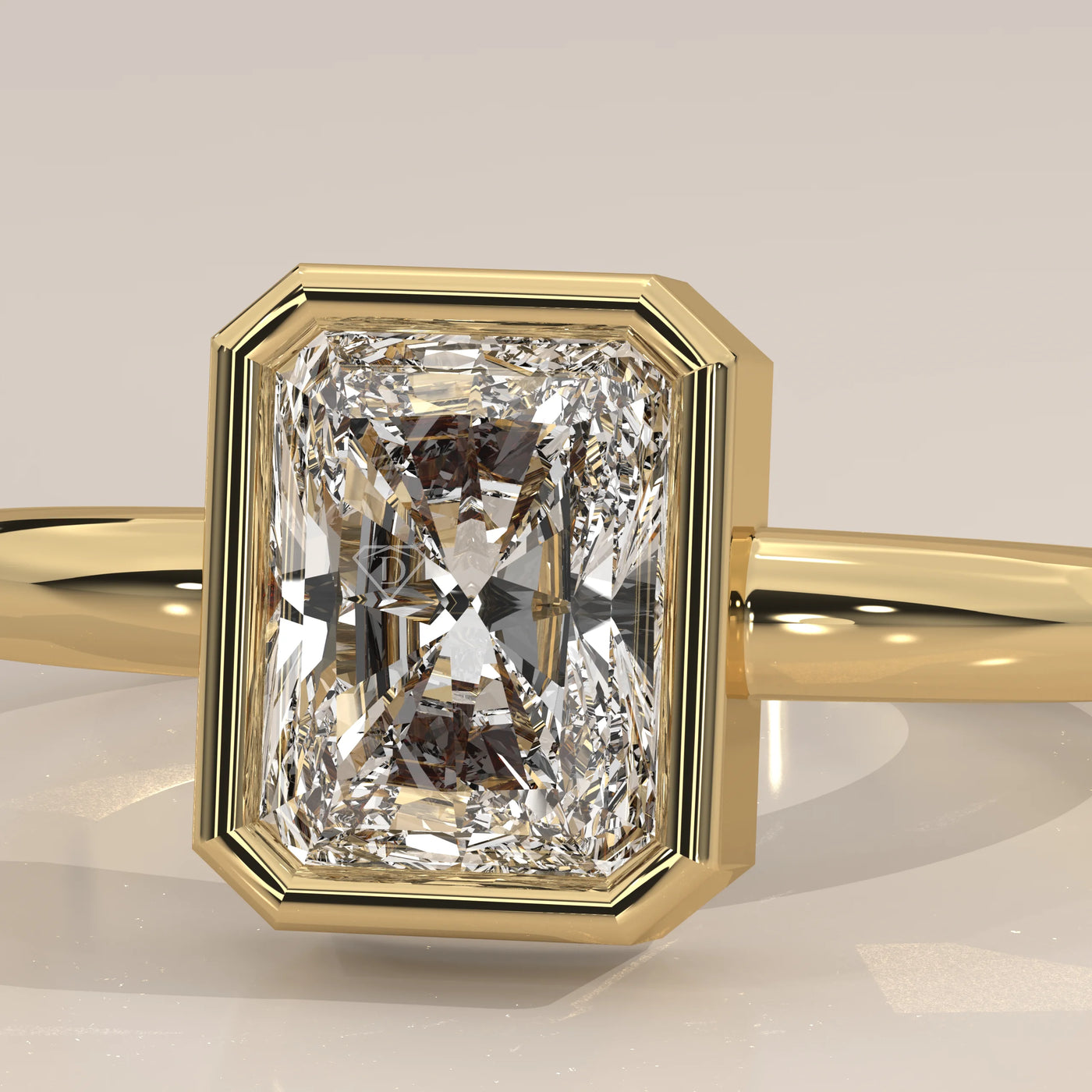 A radiant cut diamond engagement ring with a yellow gold bezel setting.