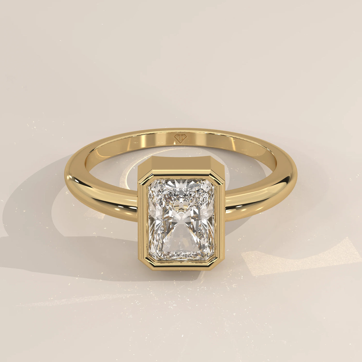 A yellow gold ring with a radiant cut diamond in a bezel setting.