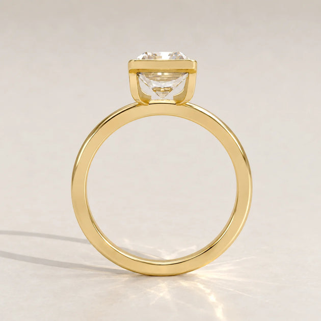 A 14k yellow gold ring with a cushion-cut diamond, side view.