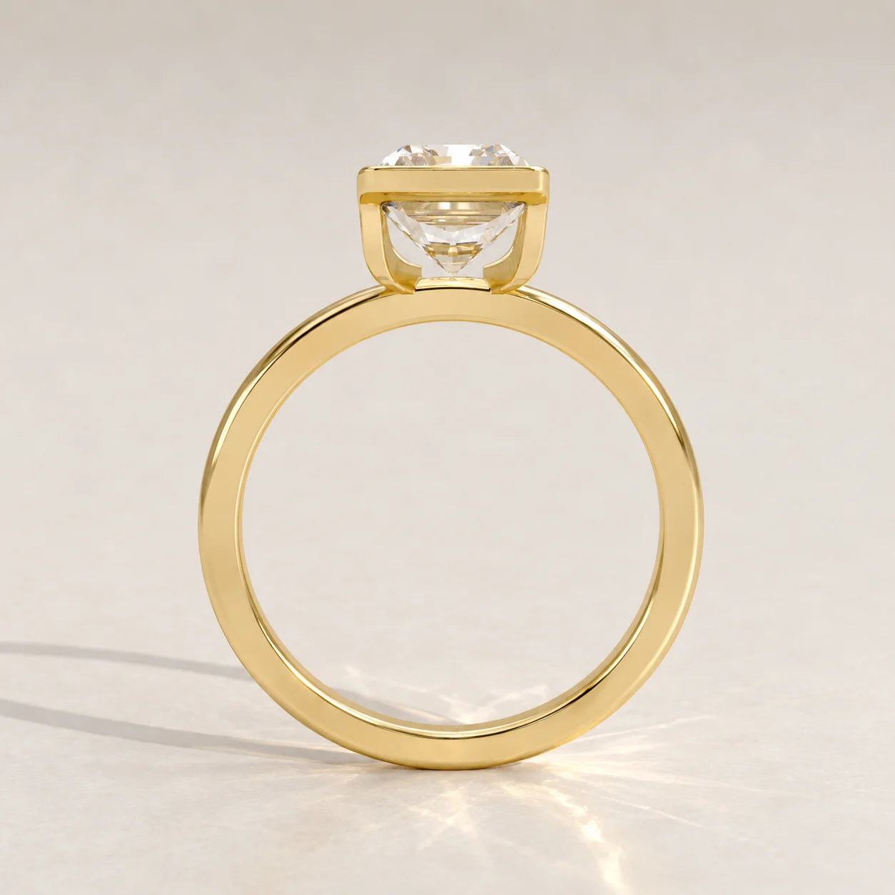A 14k yellow gold ring with a cushion-cut diamond, side view.