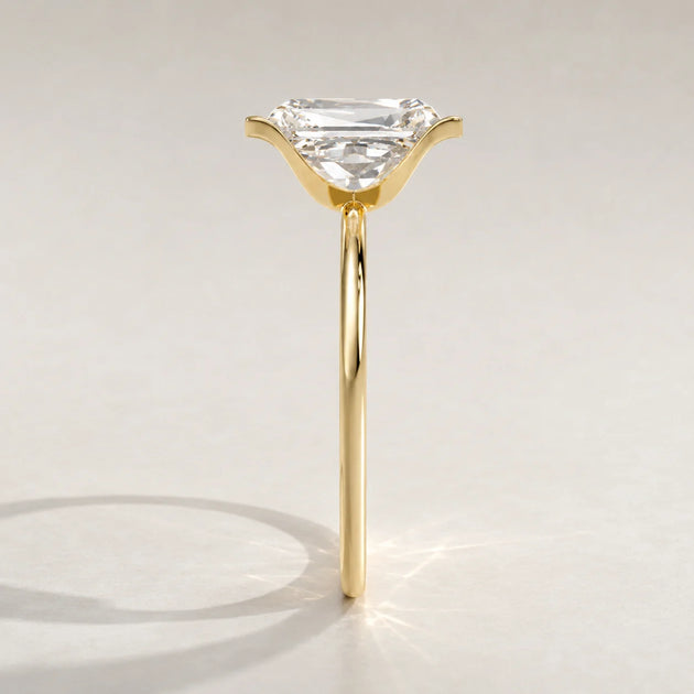 A yellow gold ring with an emerald-cut diamond set in a subtle claw setting.