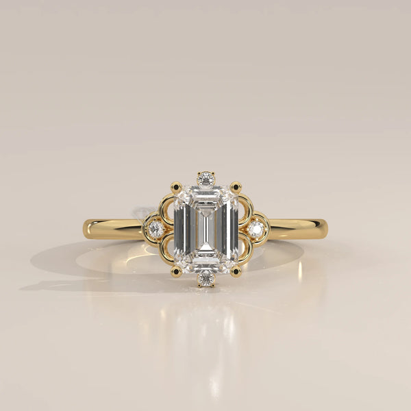 Elegant 14k yellow gold ring with an emerald-cut diamond and smaller accent stones.