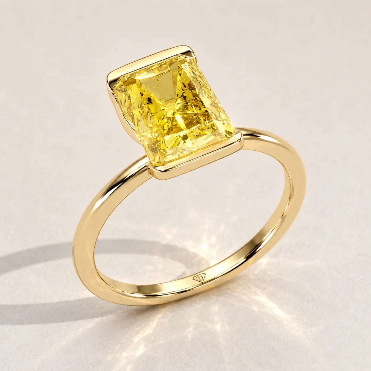 Gold ring with a prominent emerald-cut yellow diamond set horizontally.