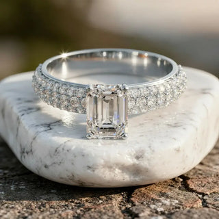 Emerald cut lab grown diamond engagement ring with a triple-row pavé diamond band on a white stone.