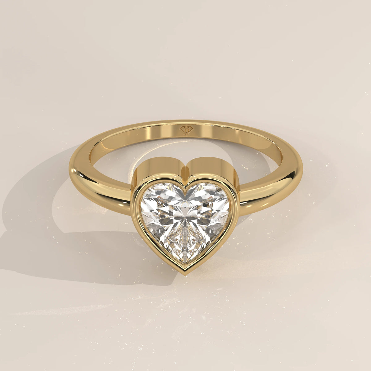 A yellow gold ring with a heart-shaped diamond in a bezel setting.