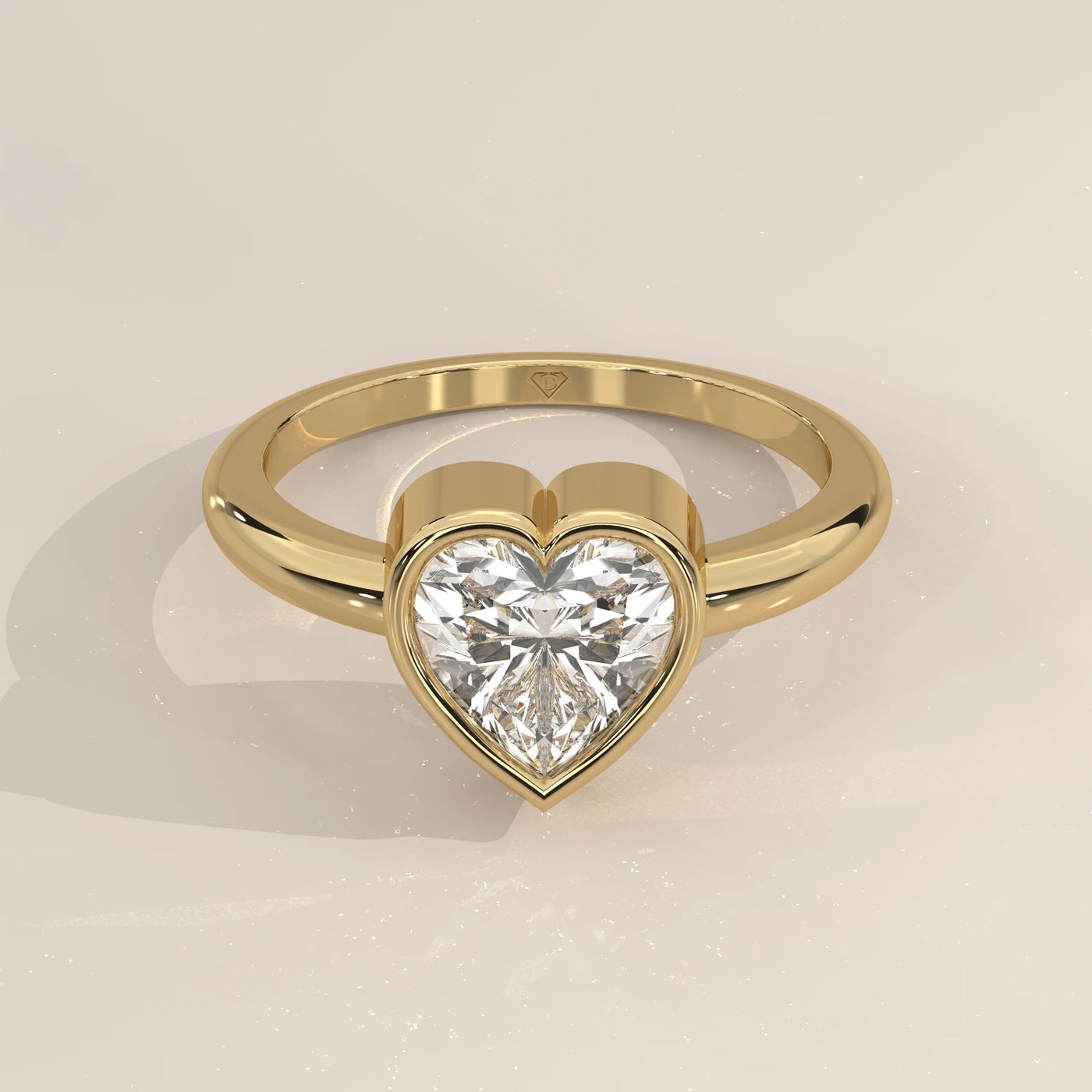 A yellow gold ring with a heart-shaped diamond in a bezel setting.