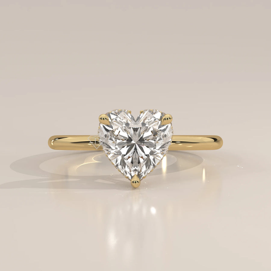 A yellow gold ring with a heart-shaped diamond in a bezel setting.