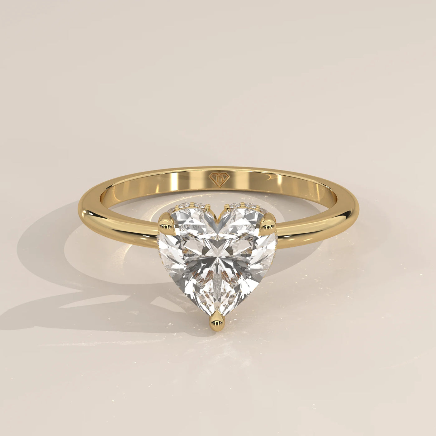 A yellow gold ring with a heart-shaped diamond in a bezel setting.