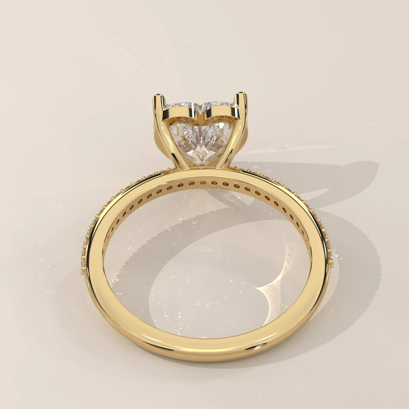 A yellow gold ring with a heart-shaped diamond and pave band.