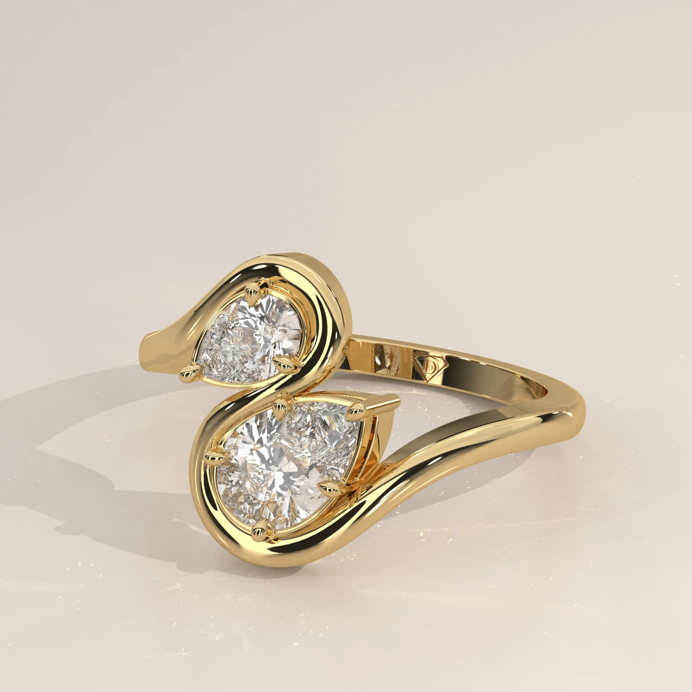 A yellow gold ring featuring two pear-shaped diamonds arranged in a swirl design.