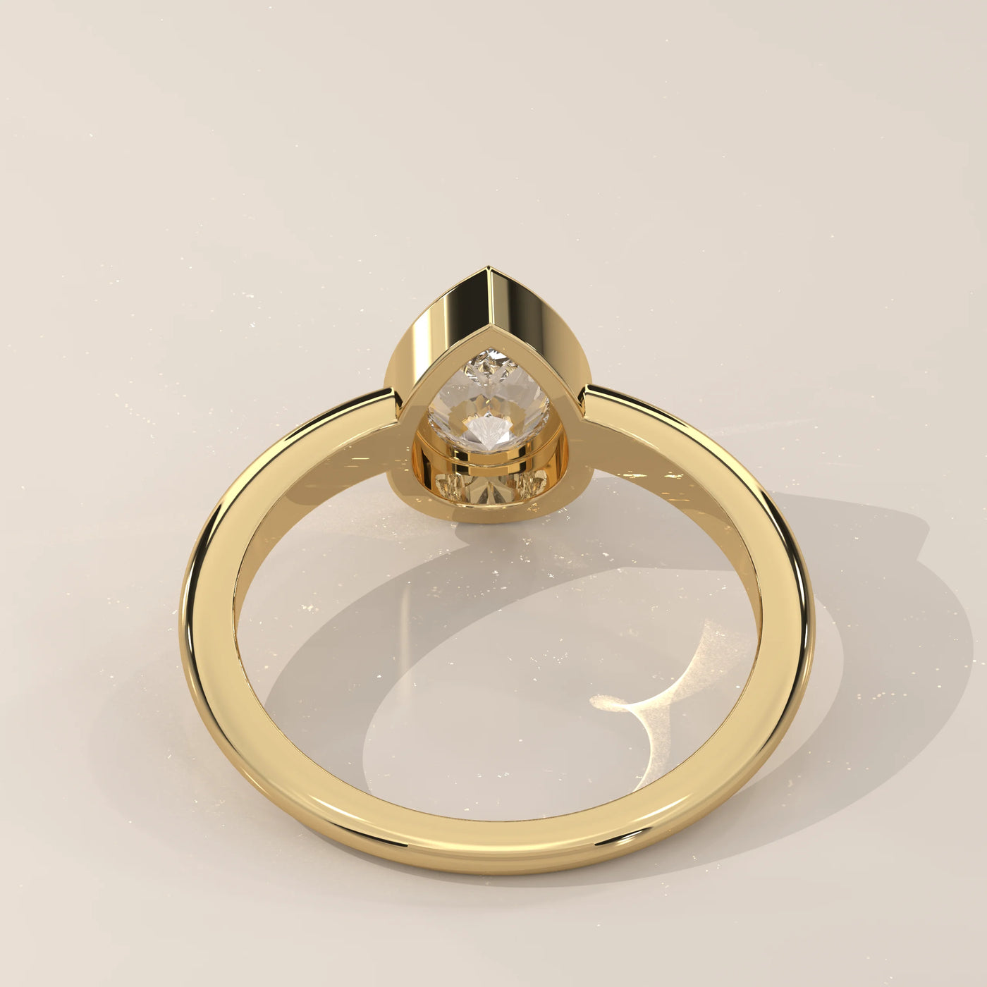 A yellow gold ring with a bezel-set pear-shaped diamond, viewed from the back.