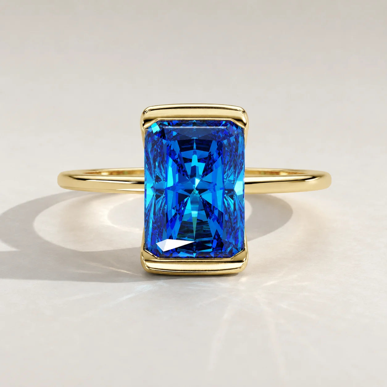 A rectangular radiant-cut sapphire ring with a gold band.