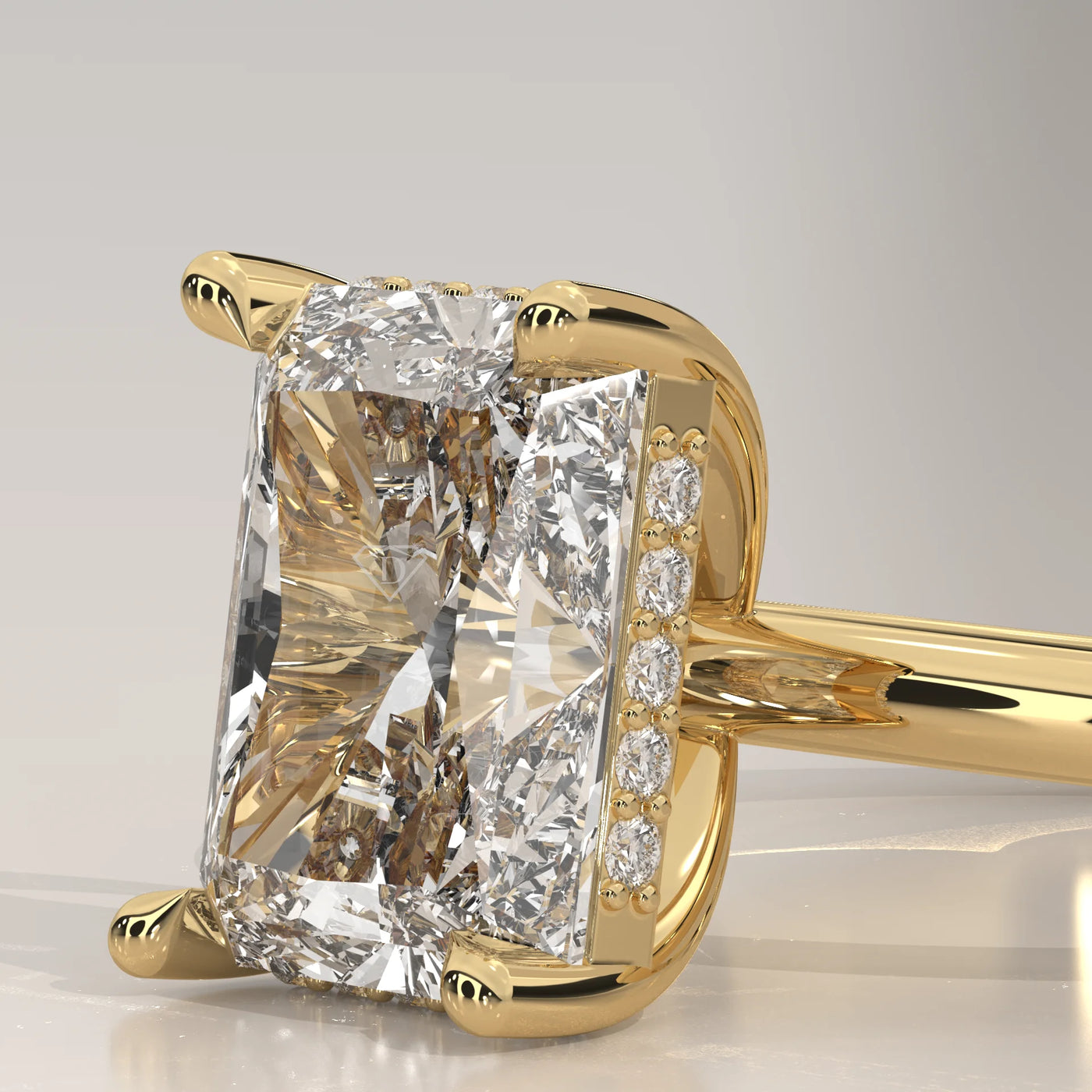Close-up of a yellow gold ring with a radiant cut diamond and pavé band.