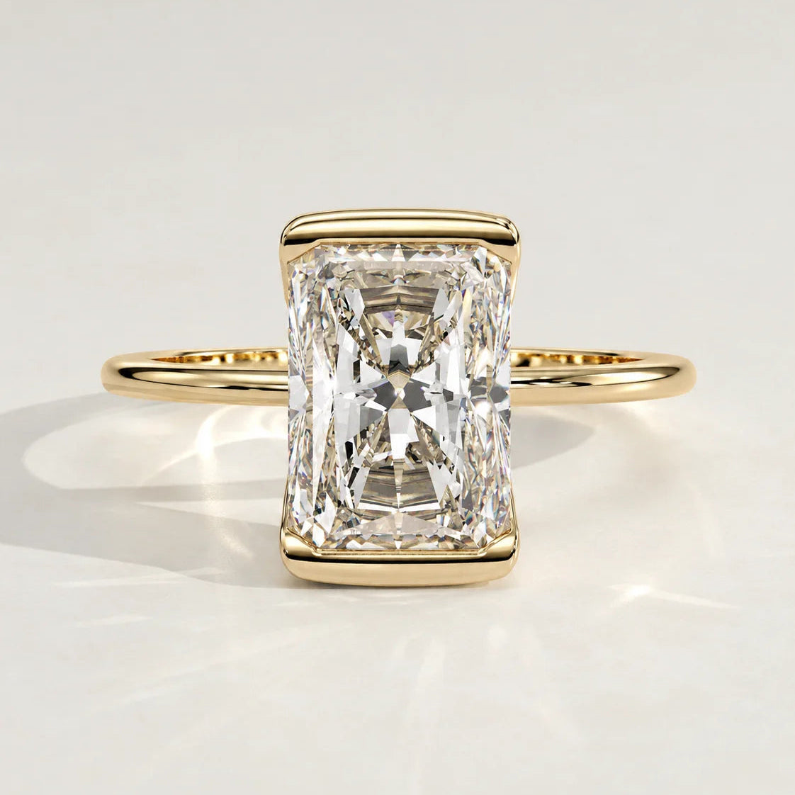 A radiant cut diamond engagement ring set in a yellow gold bezel.