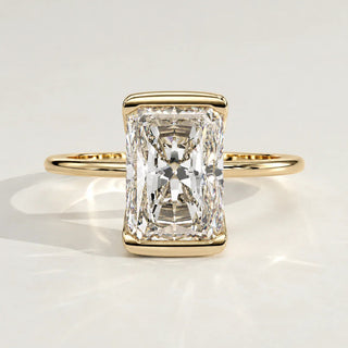 A radiant cut diamond engagement ring set in a yellow gold bezel.