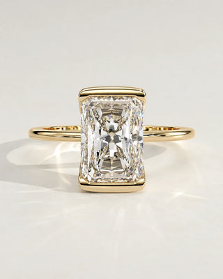 A radiant cut diamond engagement ring set in a yellow gold bezel.