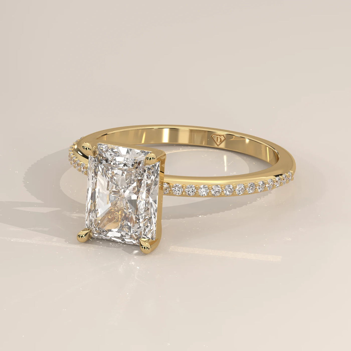A yellow gold engagement ring featuring a radiant cut diamond and pavé set side stones.