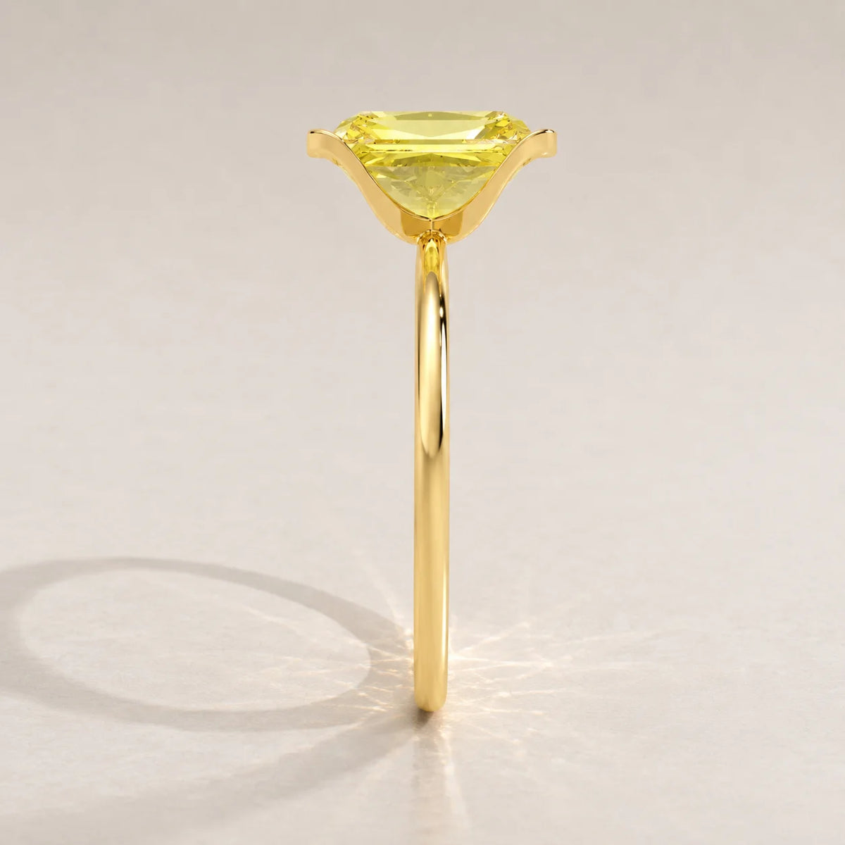 A gold ring with a rectangular yellow gemstone, side view.