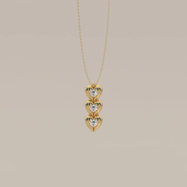 Three Puffed Heart Lab Grown Diamond Drop Pendant with Bezel Rounds in yellow gold, shown from the front.